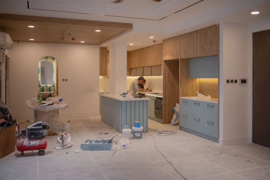 A kitchen remodel in progress, with new cabinetry and a contractor at work.