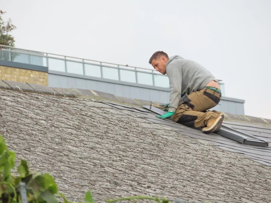 A roofer fitting material on a sloped roof.
